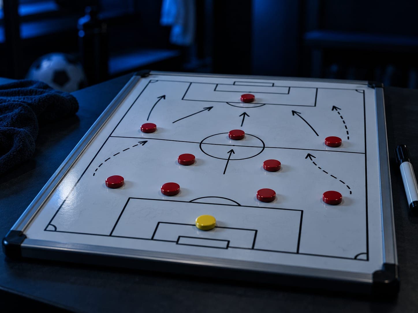 A tactics whiteboard with red and yellow magnets and arrows, on a table in a dark dressing room